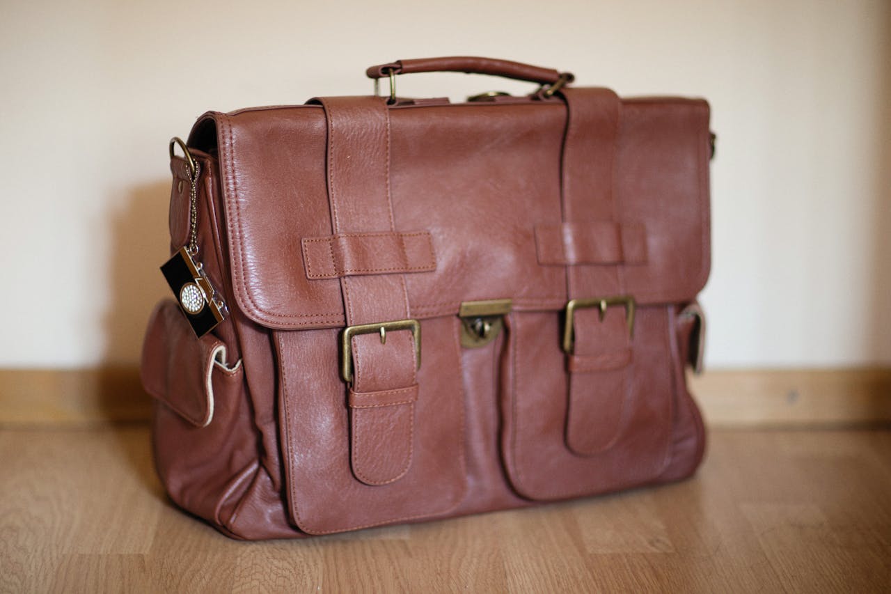 gallery-2 Stylish brown leather satchel on wooden flooring, perfect for travel or business.