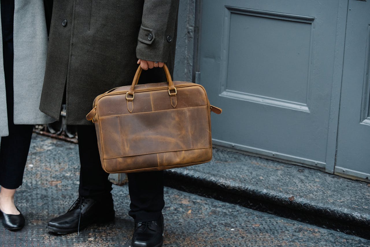 about-01 Crop unrecognizable man in elegant coat holding classy leather briefcase while standing on street with female colleague