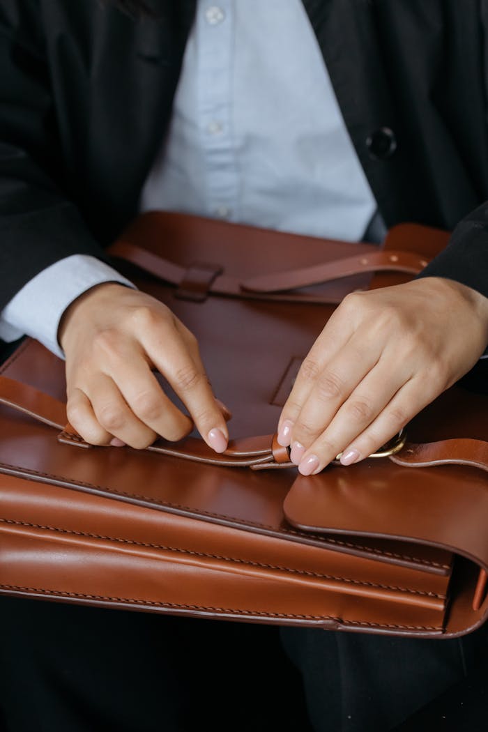 services-03 A person skillfully opening a brown leather briefcase indoors, showcasing elegant hand movements.
