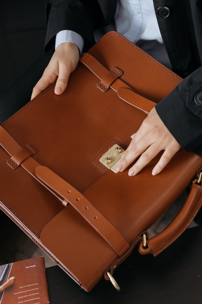 gallery-6 Close-up view of hands handling a stylish brown leather briefcase, perfect for business settings.